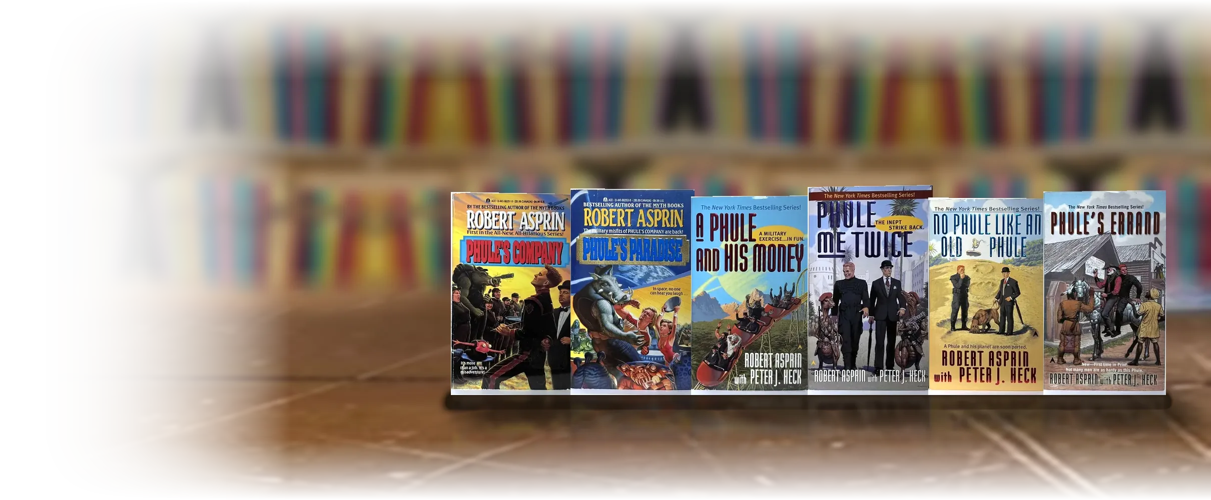Six out-of-print Phule's Company paperbacks by Robert Asprin standing upright on a wooden table.