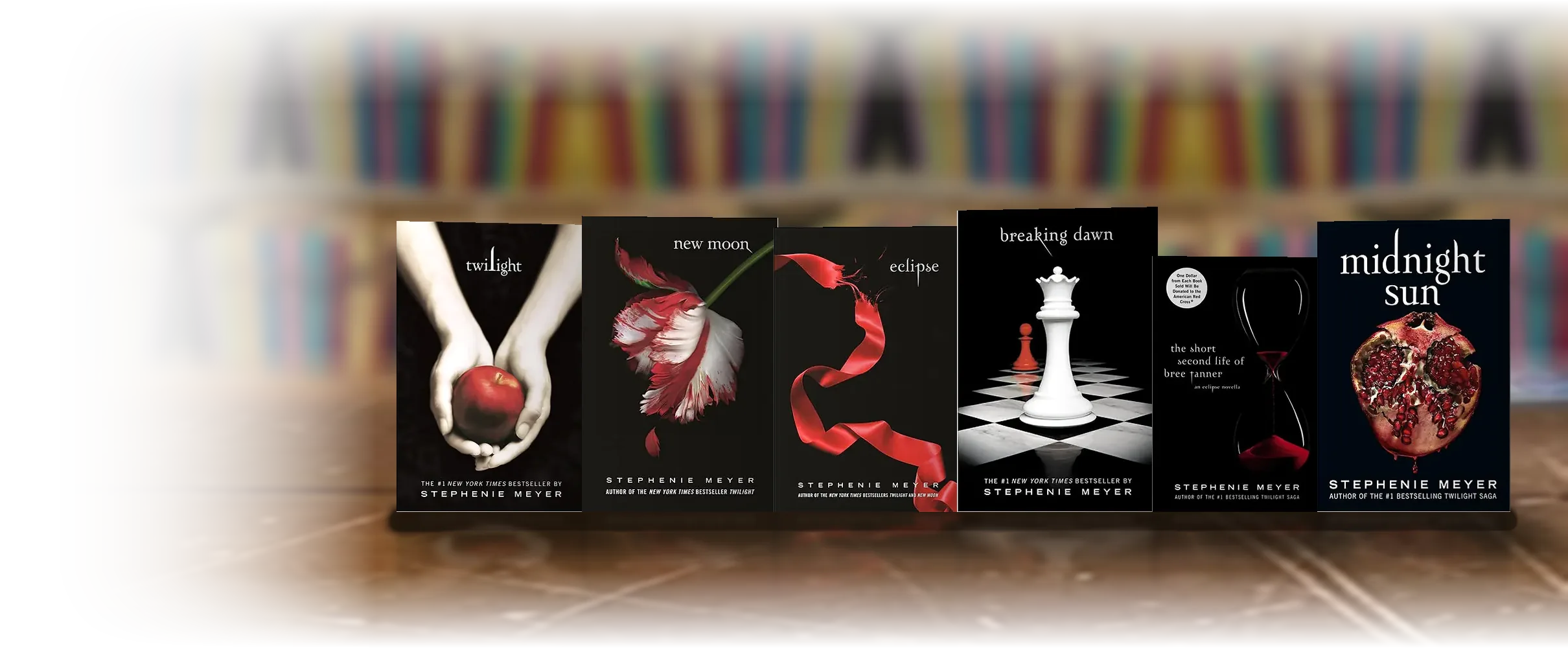 All six volumes of the Twilight saga standing upright on a wooden table.